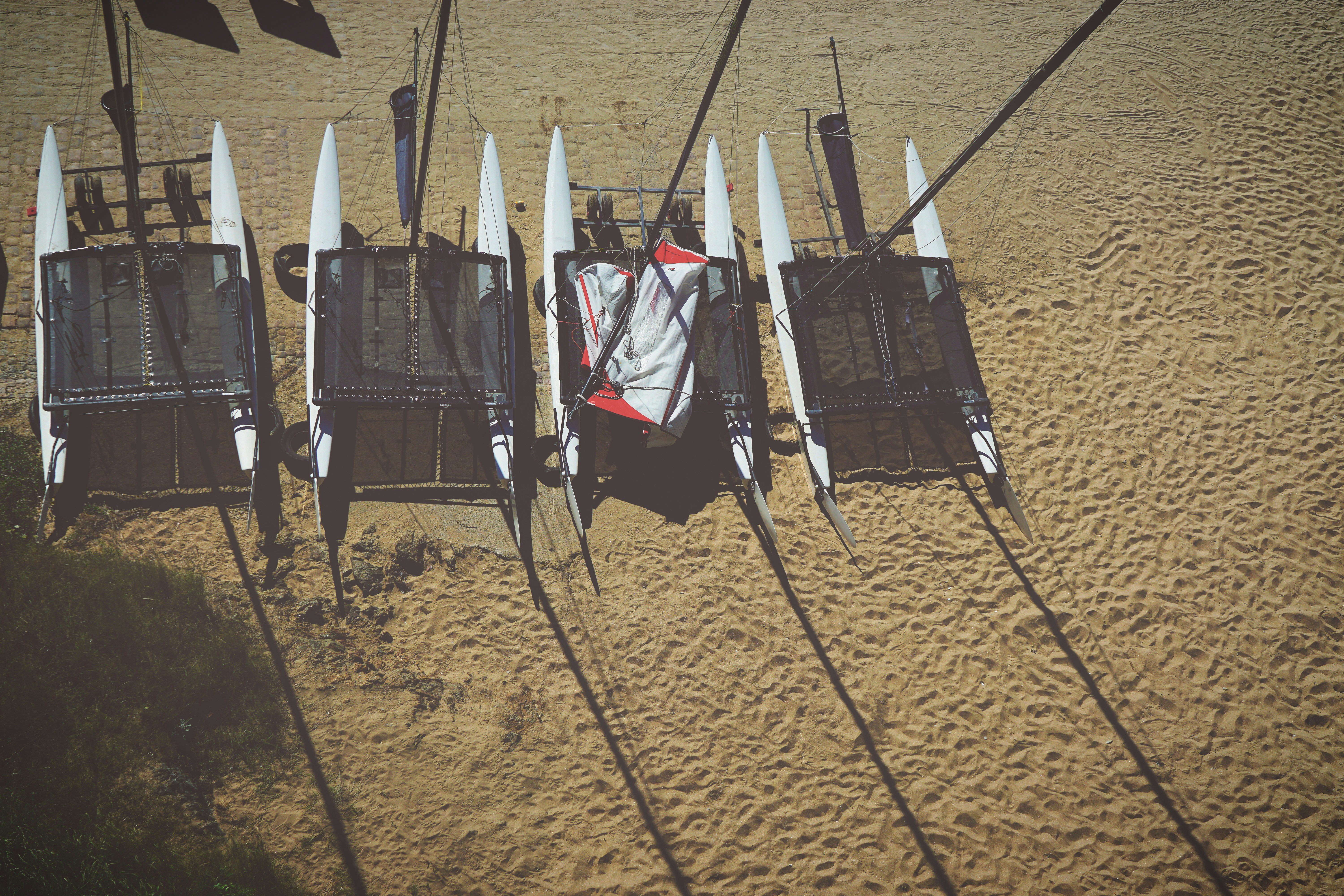 four white pontoon boats on beige sand